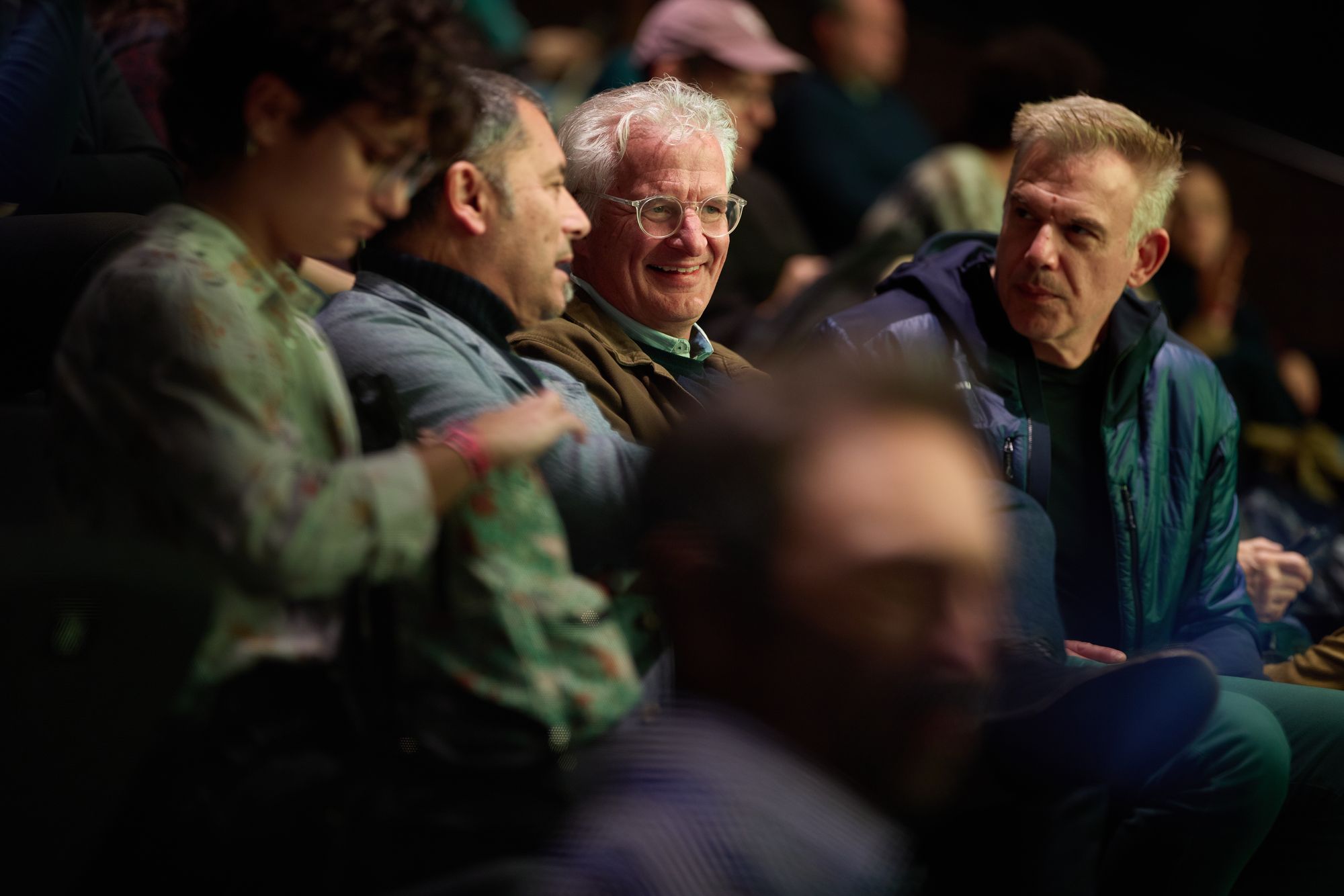 A close-up of attendees chatting in the rows.